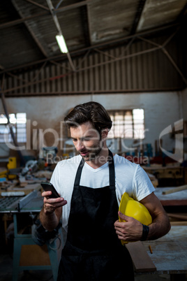 Carpenter texting someone and holding his helmet