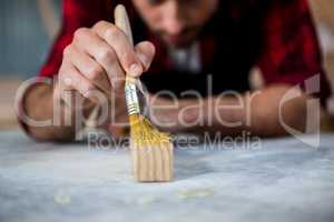 Carpenter painting a piece of wood