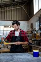 Carpenter painting a piece of wood