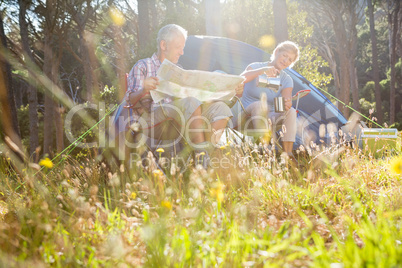 Senior couple relaxing beside their tent