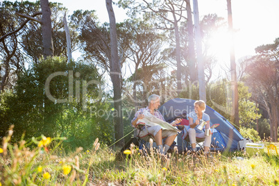 Senior couple relaxing beside their tent