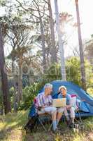 Senior couple relaxing beside their tent