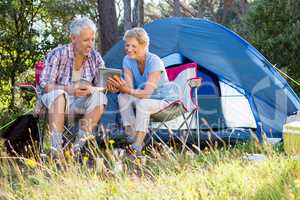 Senior couple relaxing beside their tent