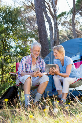 Senior couple relaxing beside their tent Senior couple relaxing beside their tent