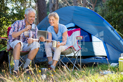 Senior couple relaxing beside their tent