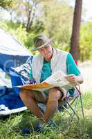 senior man reading beside his tent