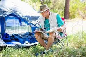 senior man reading beside his tent