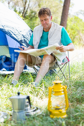 senior man reading beside his tent