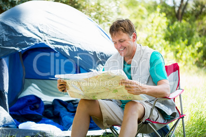 senior man reading beside his tent