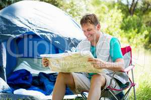 senior man reading beside his tent