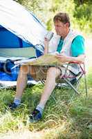 senior man reading beside his tent