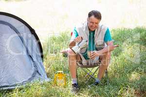 senior man is crouching beside his tent