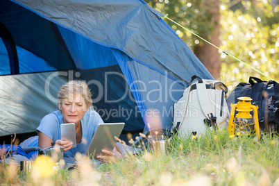 Mature woman looking her smartphone and holding a tablet