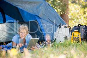 Mature woman looking her smartphone and holding a tablet