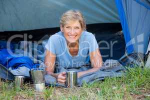 Mature woman laying smiling and holding a mug
