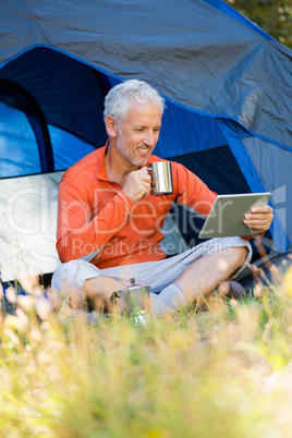 Mature man smiling and holding mug and laptop