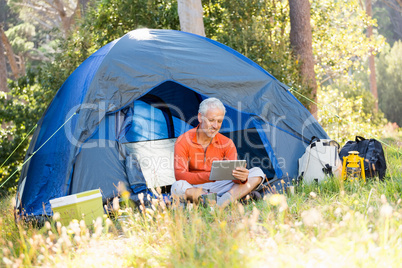 Mature man smiling and looking tablet