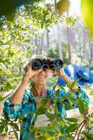 Mature woman smiling and looking on binoculars