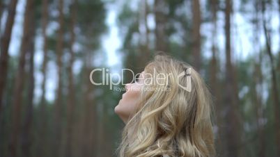 blonde woman in the forest looking up