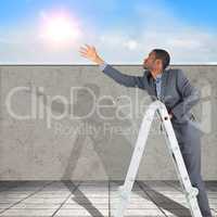 Composite image of businessman looking on a ladder