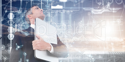 Composite image of businessman in suit holding his laptop proudl