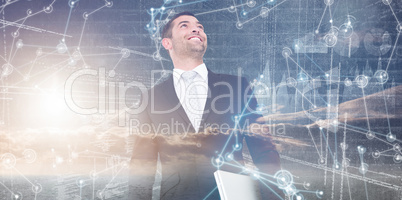 Composite image of businessman looking up holding laptop