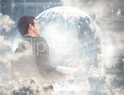 Composite image of businessman looking up holding laptop