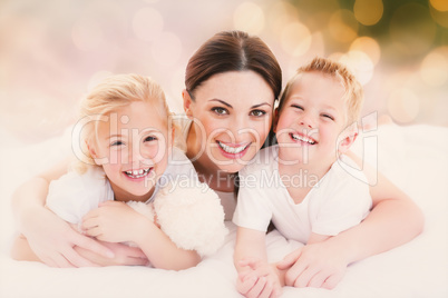 Composite image of happy mother and her children lying on a bed