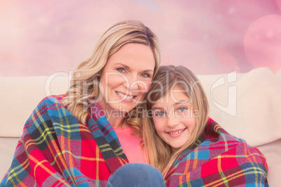 Composite image of smiling mother and daughter covered in blanke