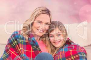 Composite image of smiling mother and daughter covered in blanke