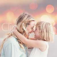 Composite image of mother and daughter rubbing noses on sofa