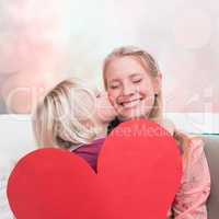 Composite image of happy mother and daughter on the couch with heart card