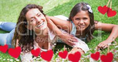 Composite image of mother and daughter lying on grass