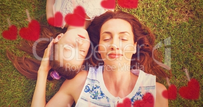 Composite image of mother and daughter lying on a park