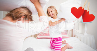 Composite image of mother and daughter fighting with pillows