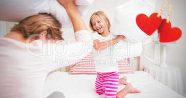 Composite image of mother and daughter fighting with pillows