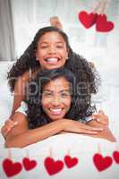 Composite image of mother and daughter smiling and lying on a be