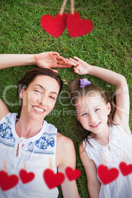 Composite image of mother and daughter lying on grass