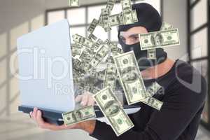 Composite image of focused burglar with balaclava holding laptop