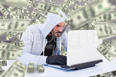 Composite image of serious burglar hacking into laptop