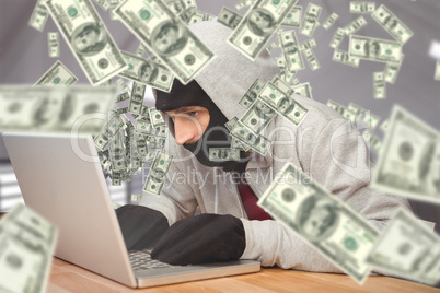 Composite image of hacker using laptop