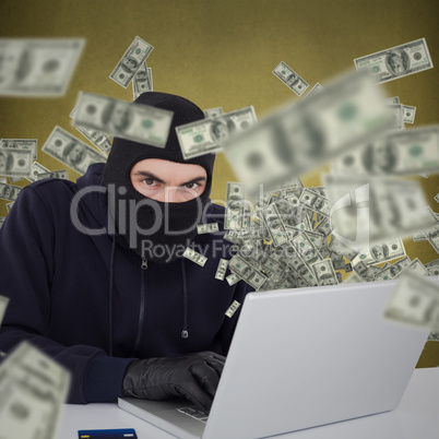 Composite image of hacker in balaclava hacking a laptop