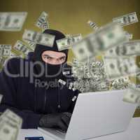 Composite image of hacker in balaclava hacking a laptop