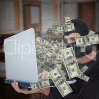 Composite image of focused burglar with balaclava holding laptop