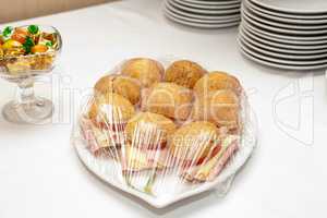 Sandwiches on a silver tray covered with transparent foil