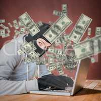 Composite image of focused thief with hood typing on laptop
