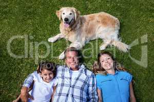 Happy family lying ion grass with their dog