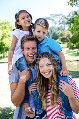 Happy parents carrying their kids on the shoulder in the park