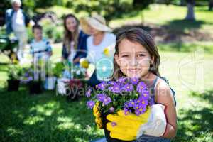 Girl holding a flower pot while gardening with family