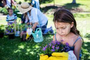 Girl holding a flower pot while gardening with family